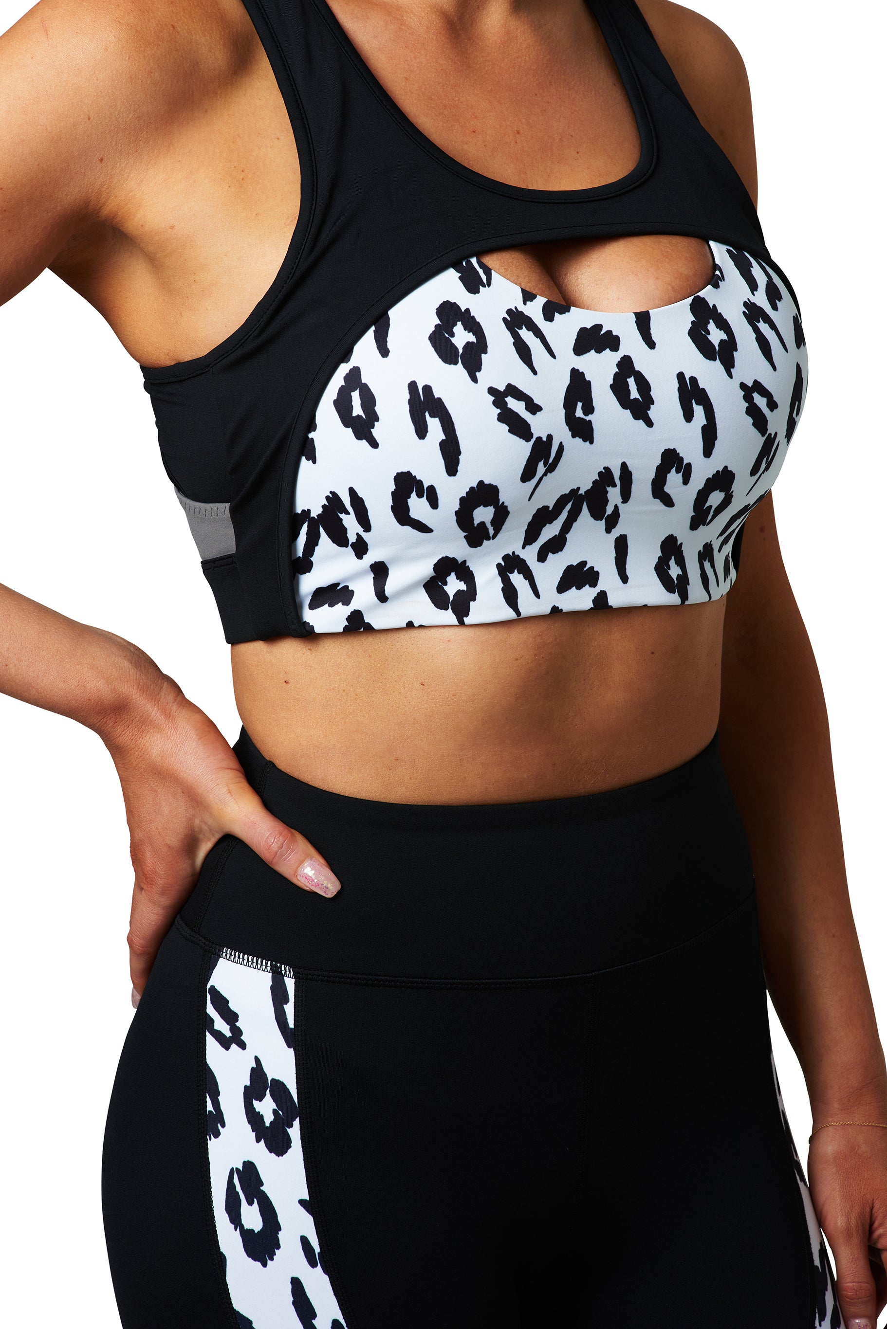 A woman wearing a BAD CAT branded black and white leopard print sports bra, paired with black activewear leggings.